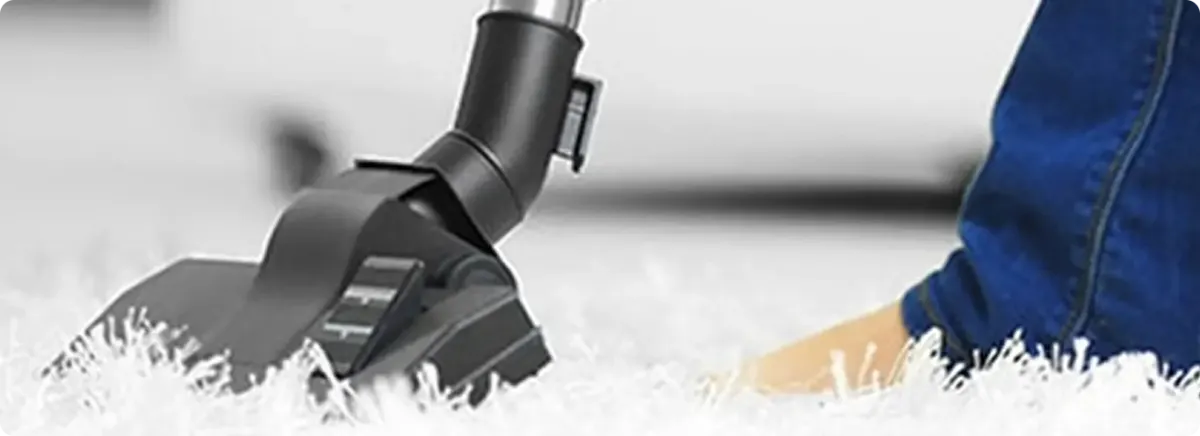 Close-up of a professional vacuuming a white carpet in Denver.